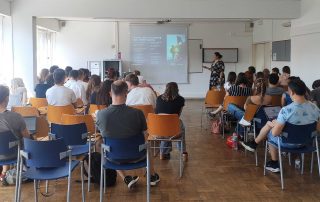 Grupo de pessoas sentadas em cadeiras numa sala de aula