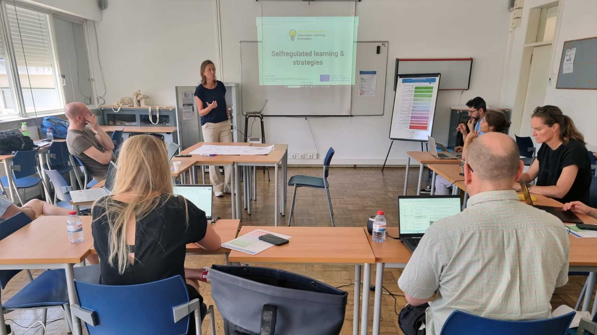 Grupo de pessoas sentadas em mesas em uma sala de aula