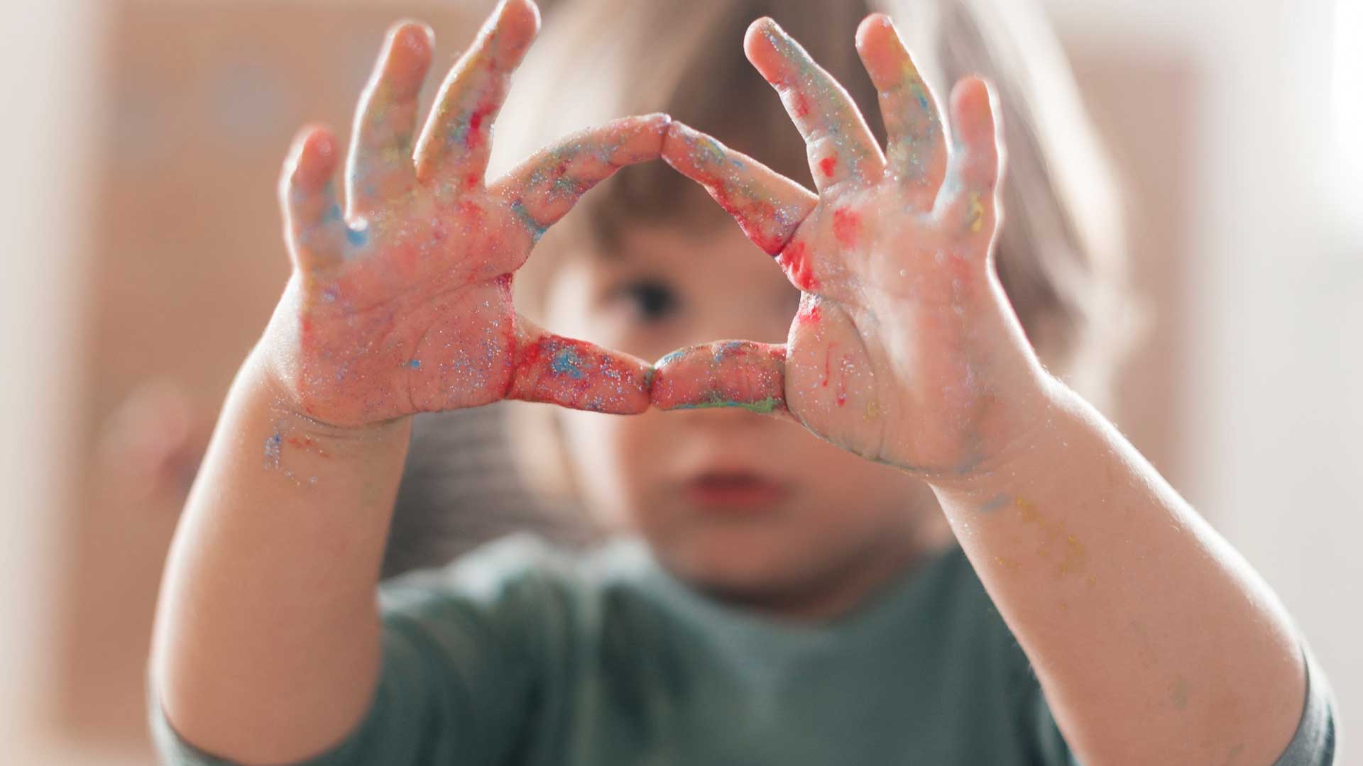 criança com as mãos sujas de tinta