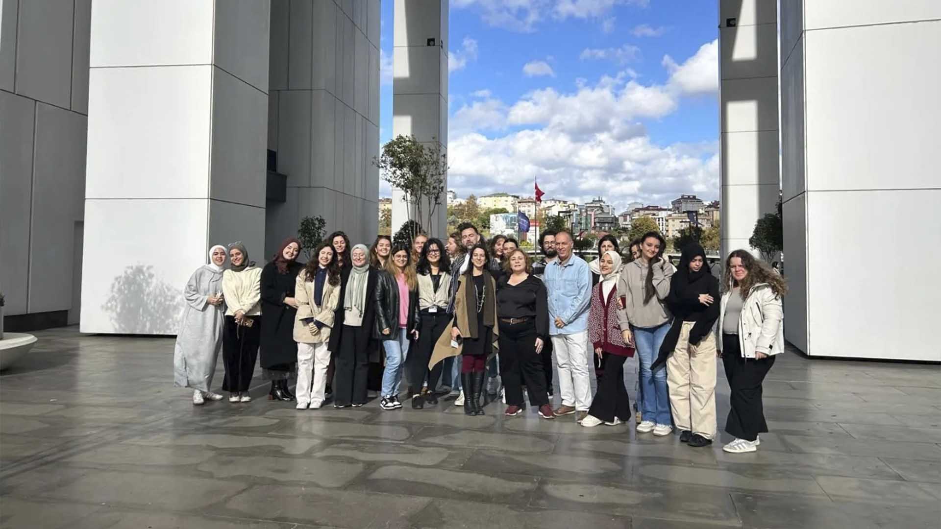 Grupo de pessoas posando em frente a um edifício e sorrindo.