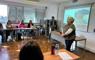 Professora e estudantes sentados numa sala de aula