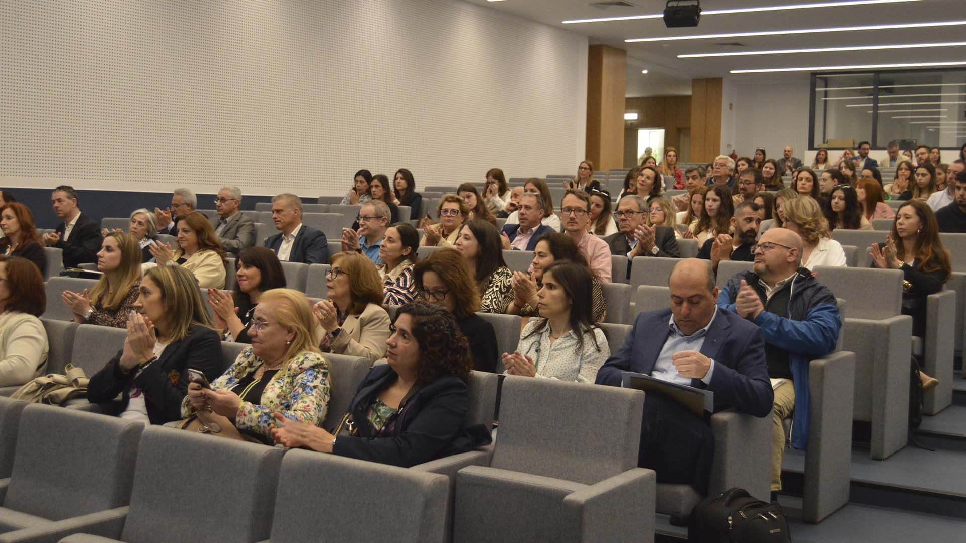 dezenas de pessoas sentadas num auditório a assistir a uma apresentação