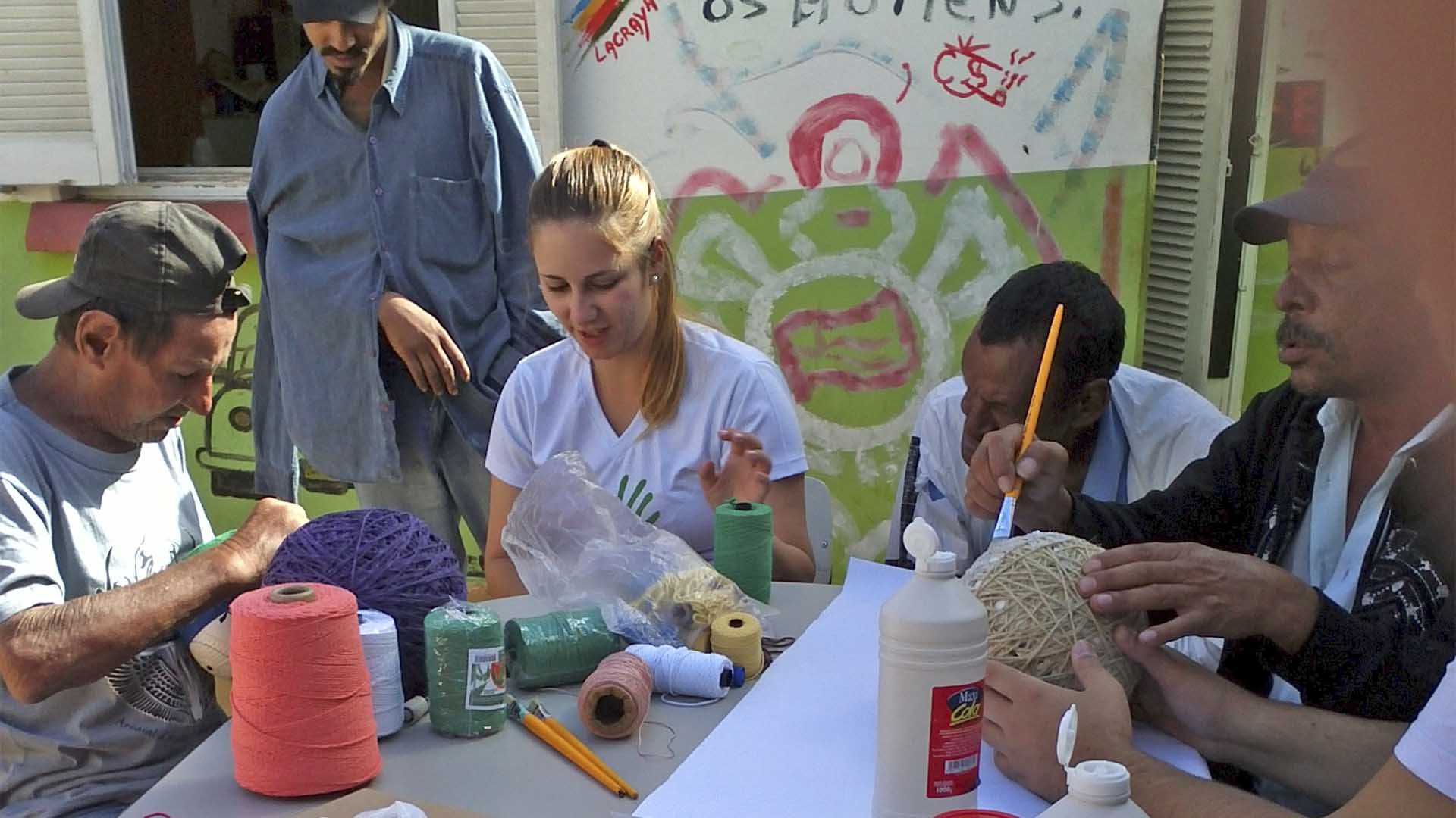 cinco pessoas sentadas em volta de uma mesa a fazer atividades de pintura